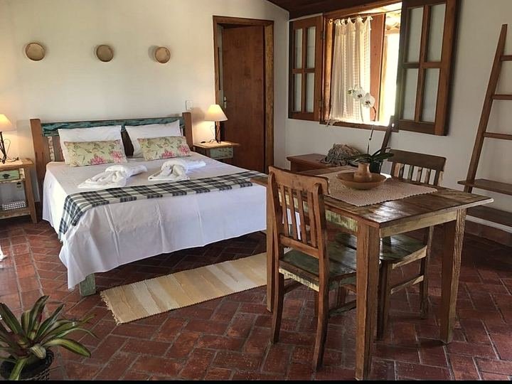 Cama queen com almofadas floridas e mesa de madeira